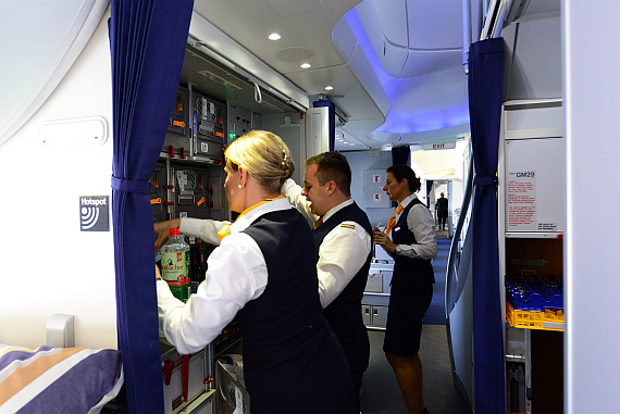  Busy Lufthansa male and female flight-attendants in crowded galley. 